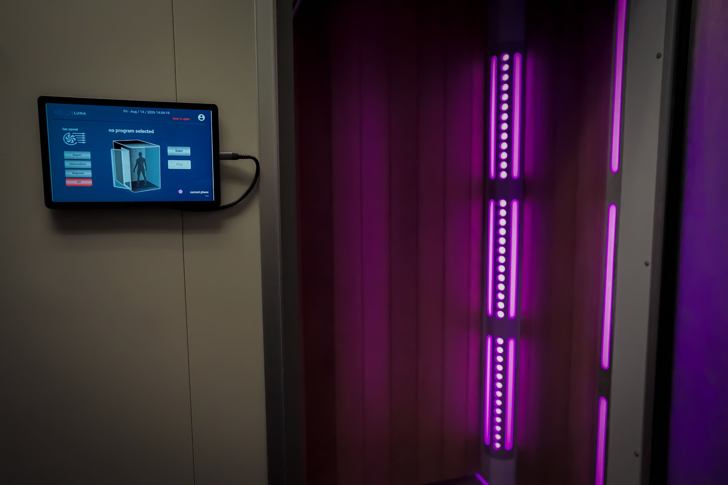 Cryotherapy chamber touchscreen beside the chamber door lit in purple