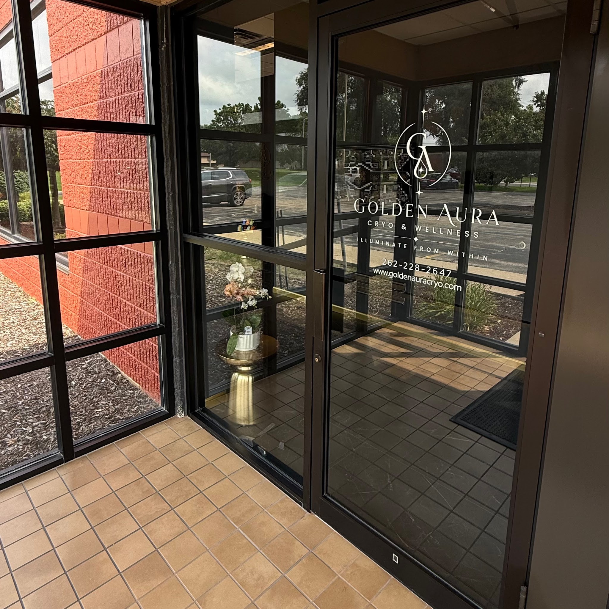 Glass entrance door with the Golden Aura logo at Suite 120