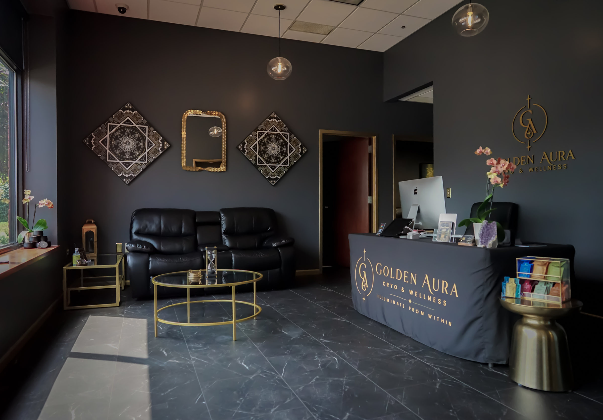 Golden Aura front desk and lounge with black leather sofas, gold mirrors and the logo on the wall